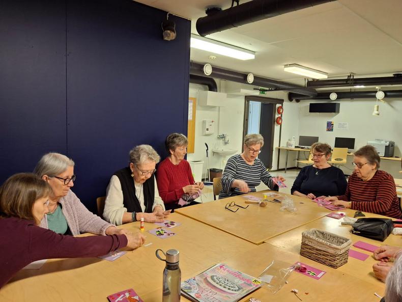 Joukko ikäihmisiä askartelemassa pöydän äärellä.