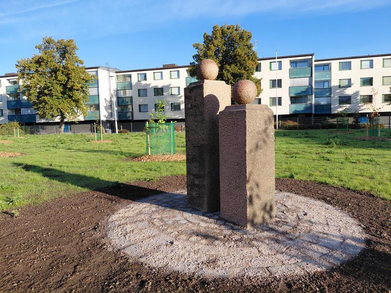 Graniittiset portinpylväät ovat vierekkäin, taustalla kerrostaloja.