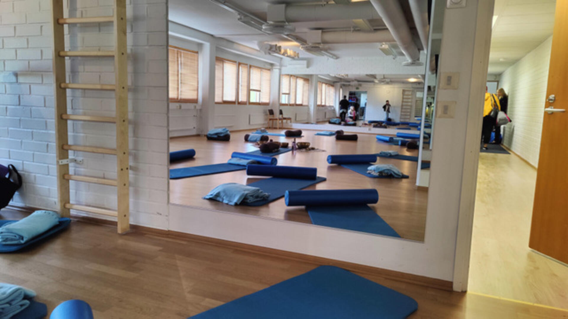 Tasalanaukion ryhmäliikuntatila, jossa näkyy parkettilattia, peili, puolapuut ja jumppamattoja.