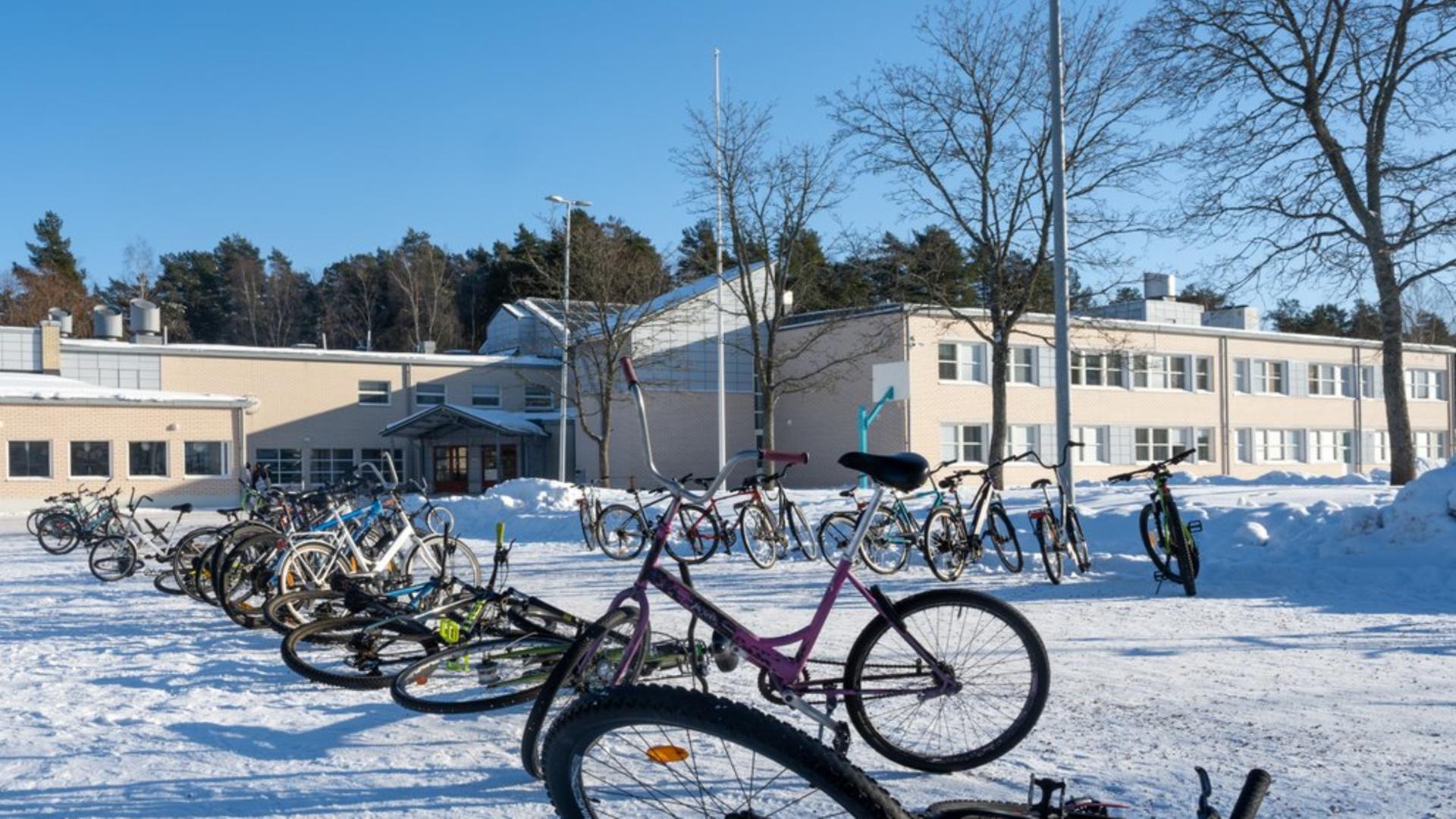 Polkupyöriä Vaisaaren koulun edessä talvisessa maisemassa.