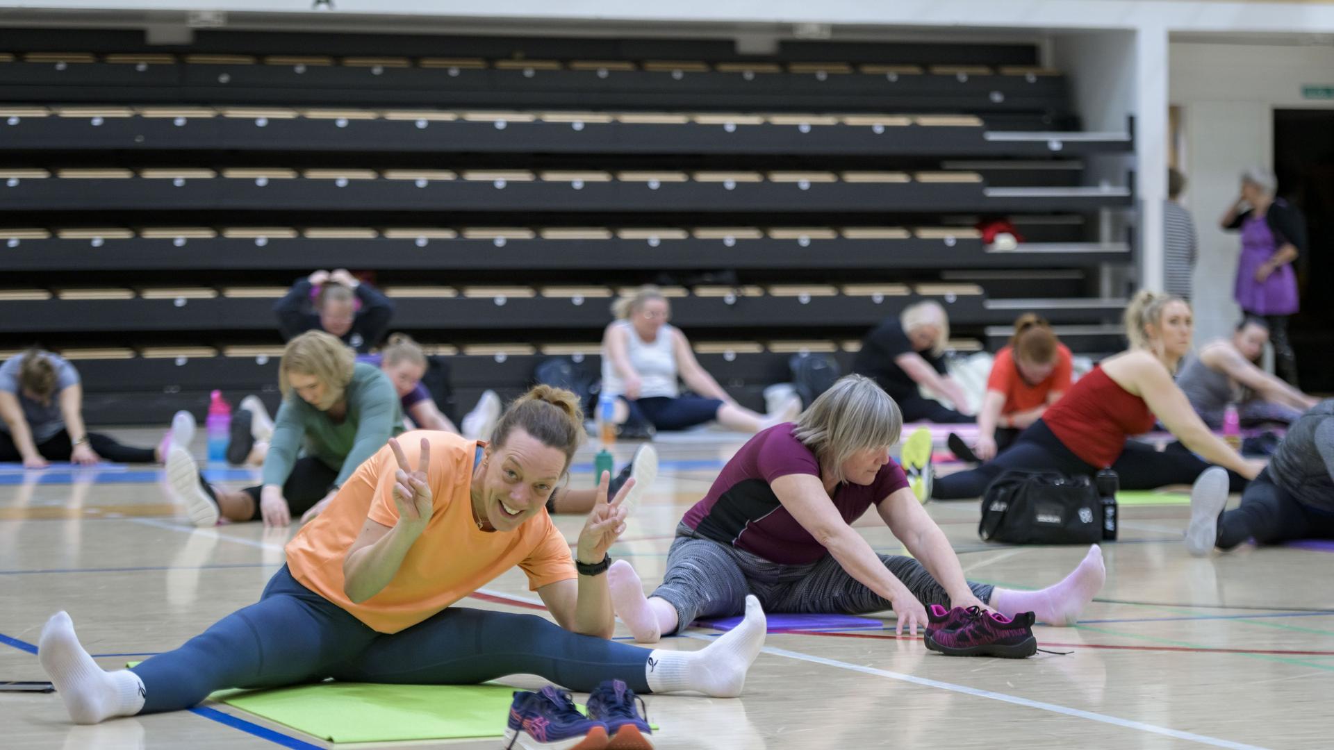 Joukko naisia venyttelemässä lattialla. 