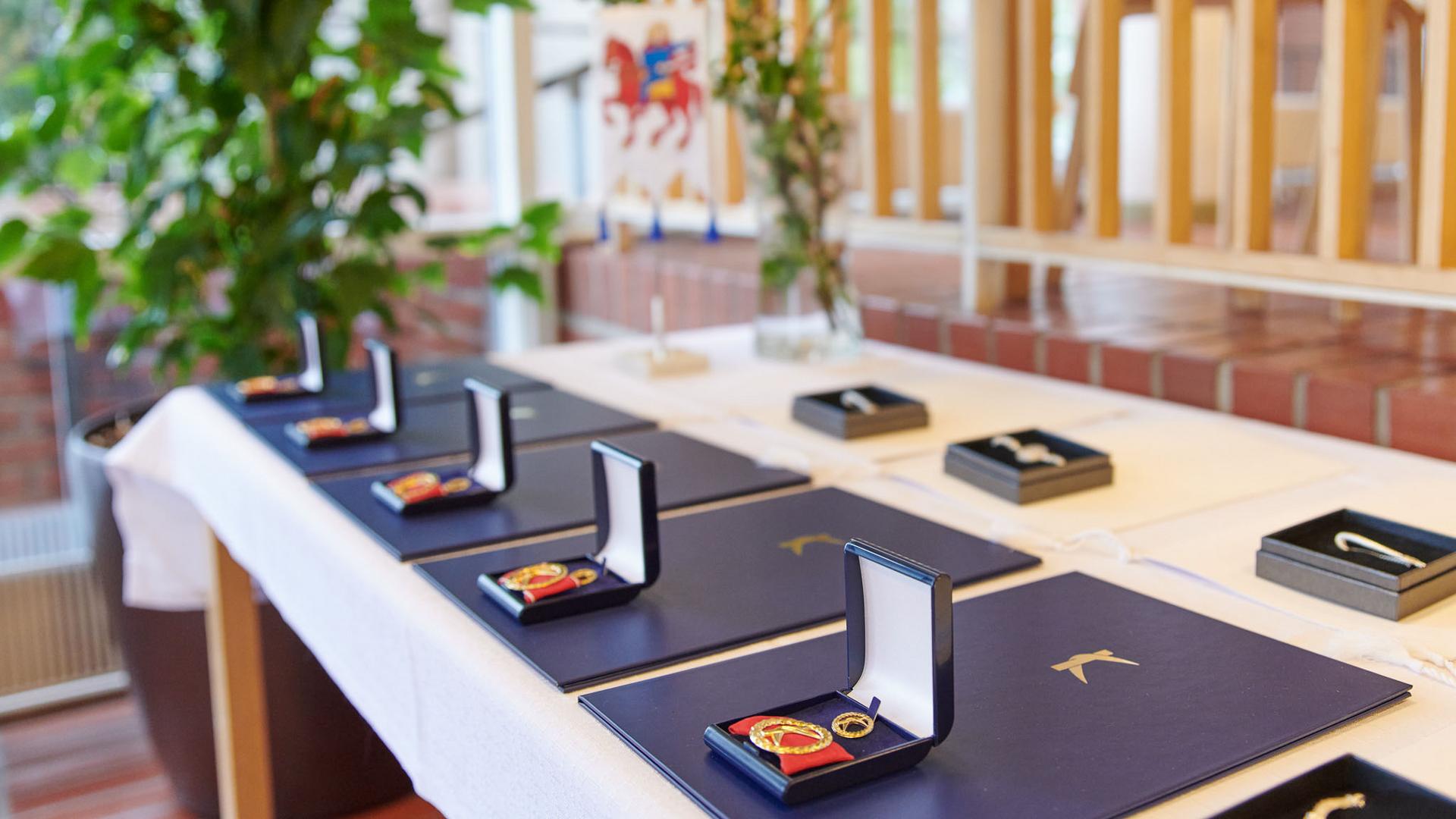 Kunniamerkkejä pöydällä, taustalla Raision vaakuna