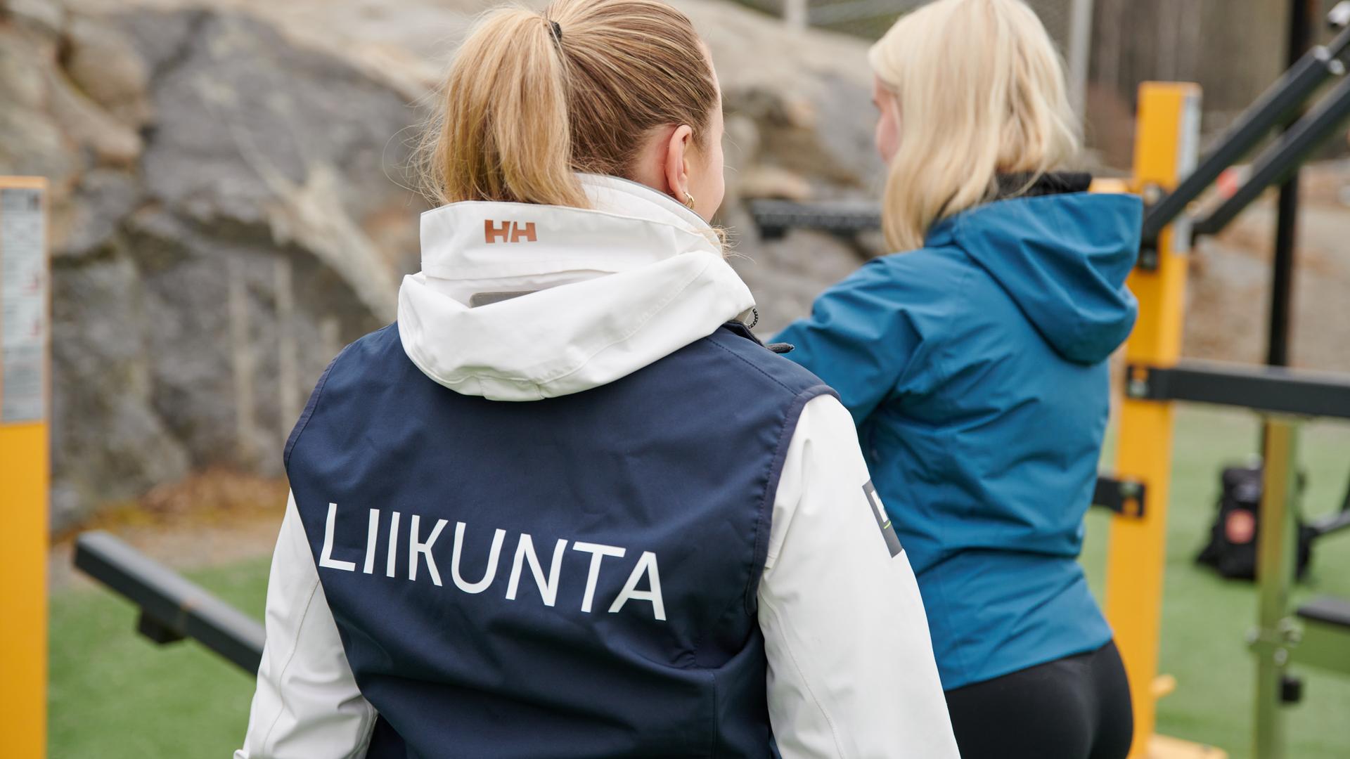 Liikuntaohjaaja neuvoo henkilöä ulkoliikunpaikassa.