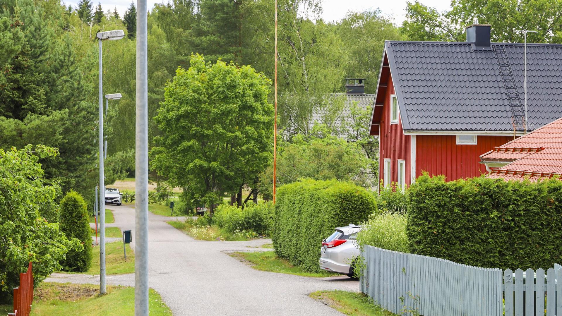 Kesäinen katumaisema, jossa punainen omakotitalo