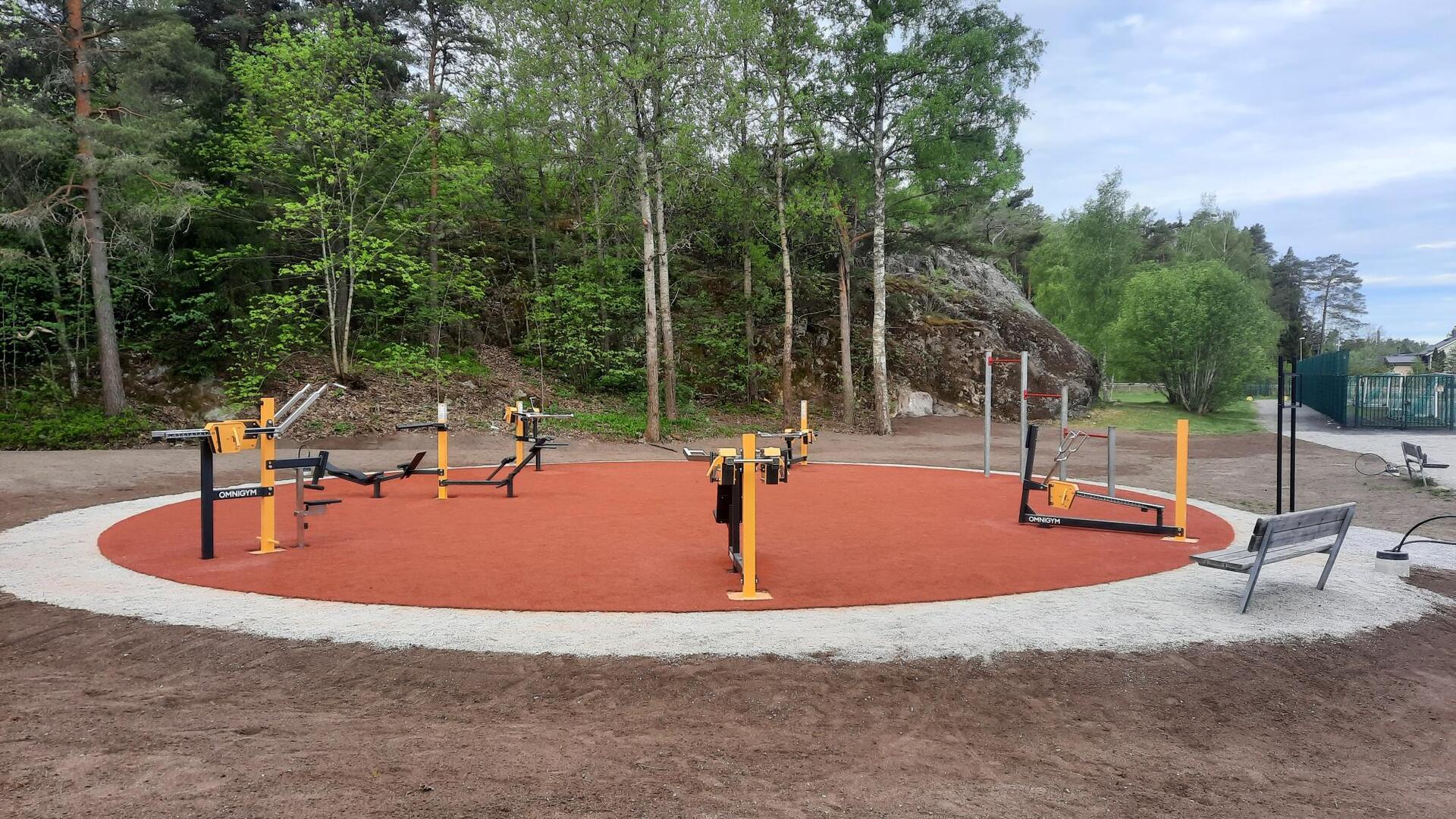 Ulkokuntosalilaitteita punaisen alustan päällä.