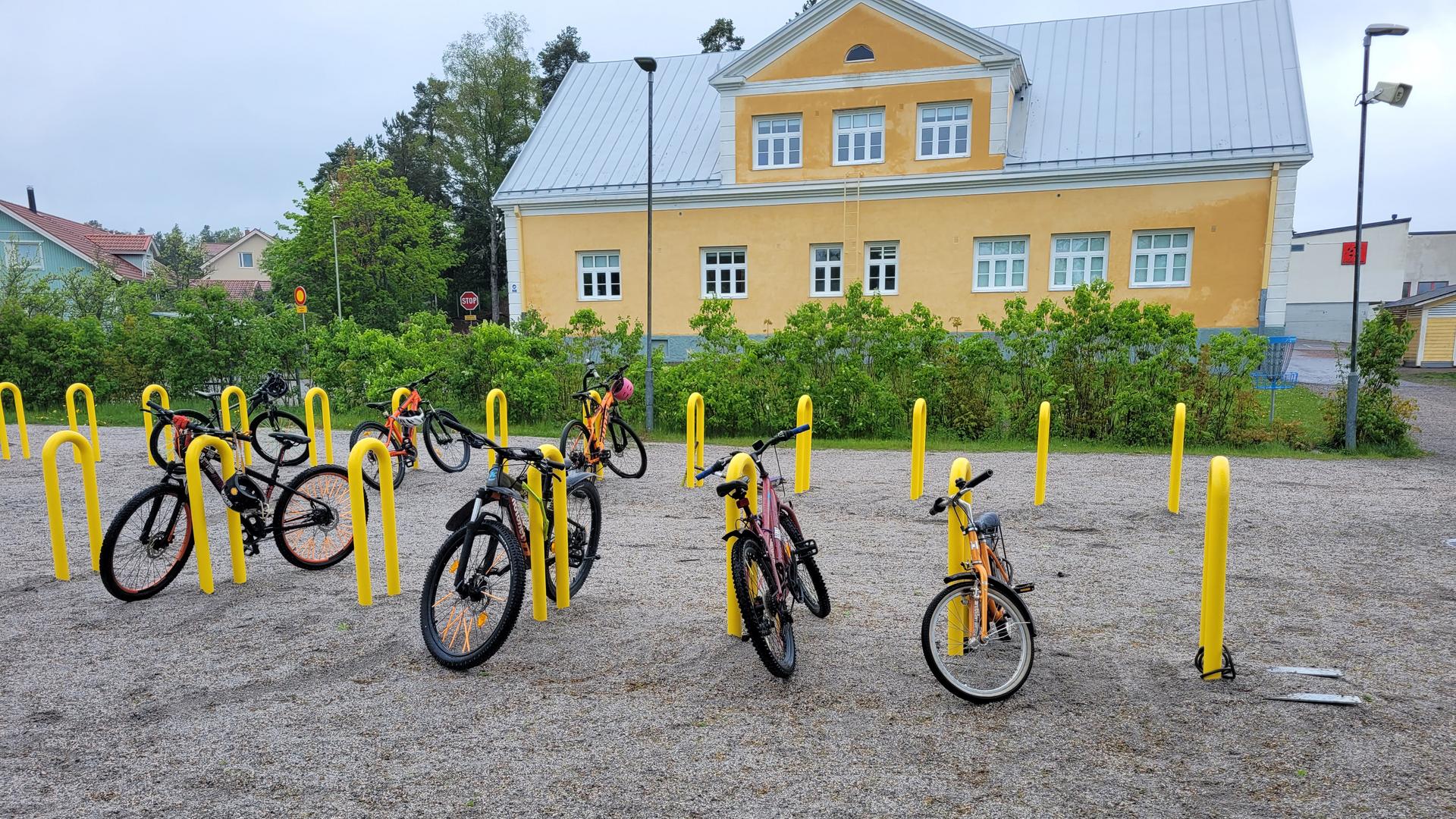 Polkupyöriä keltaisissa telineissä Kerttulan koulun pihalla