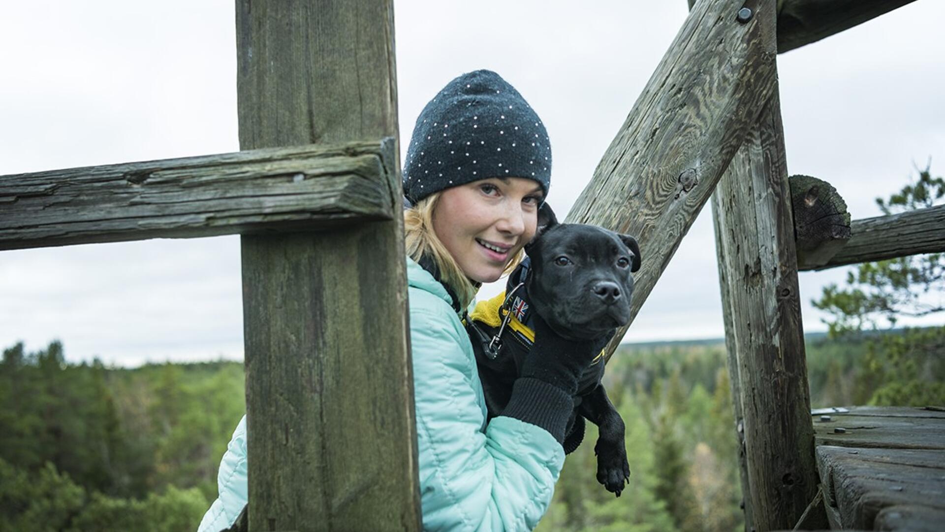 Nainen pitää koiraa sylissä näköalatornissa. 