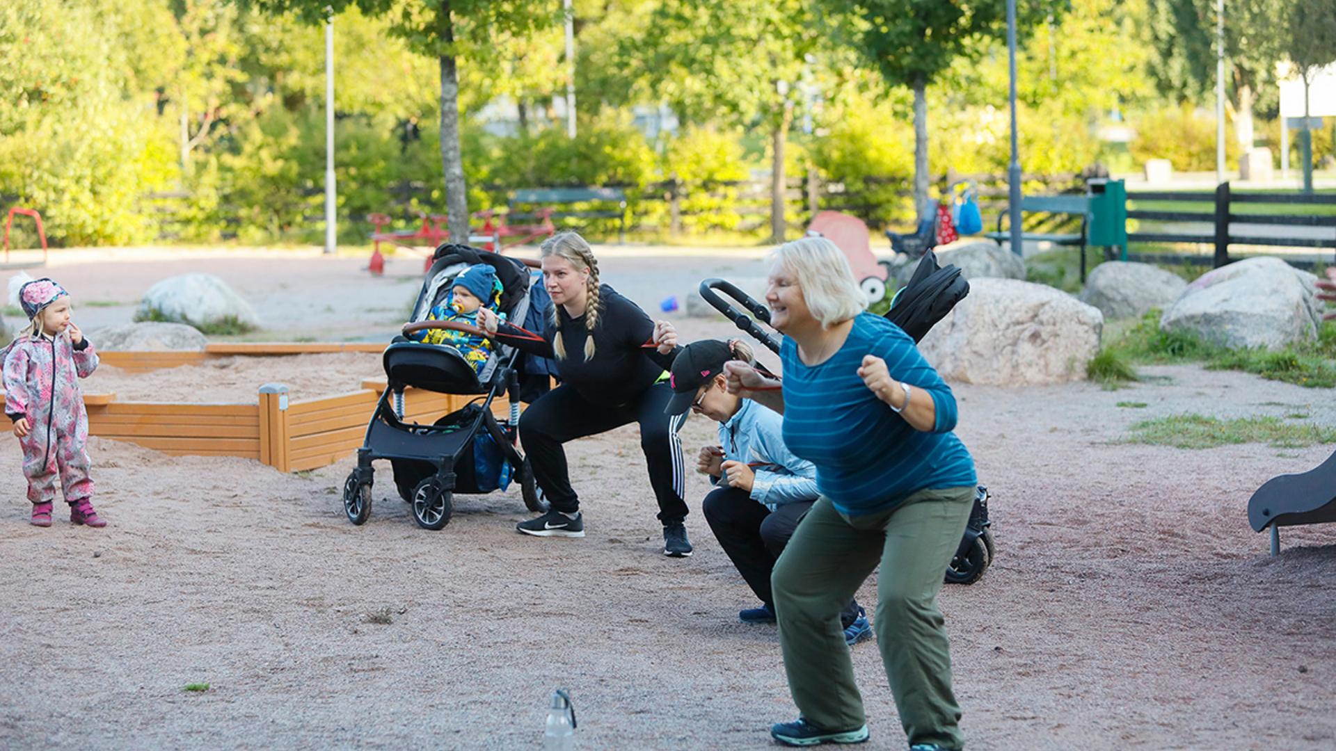 Kaiken ikäisiä ihmisiä jumppaamassa leikkipuistossa.