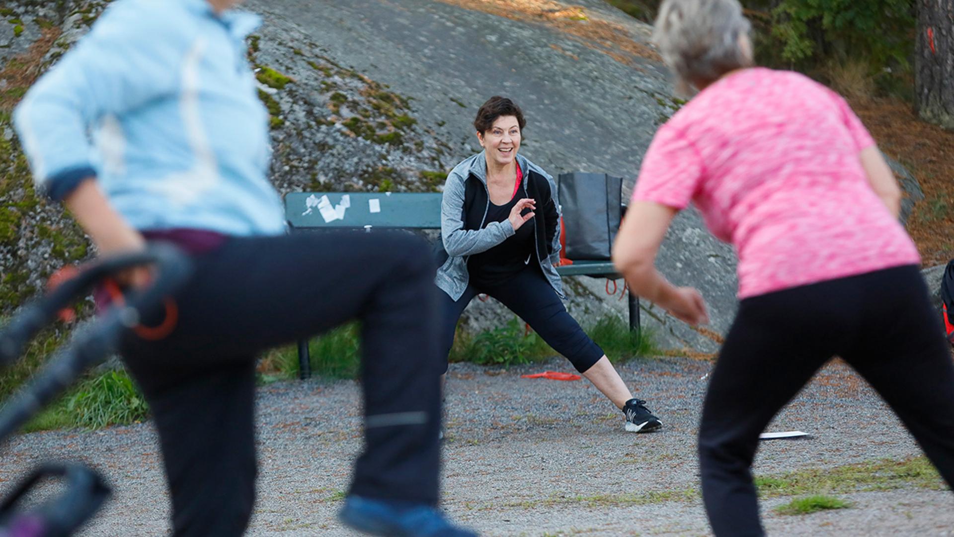 Ohjaaja pitää jumppatuokiota puistossa.