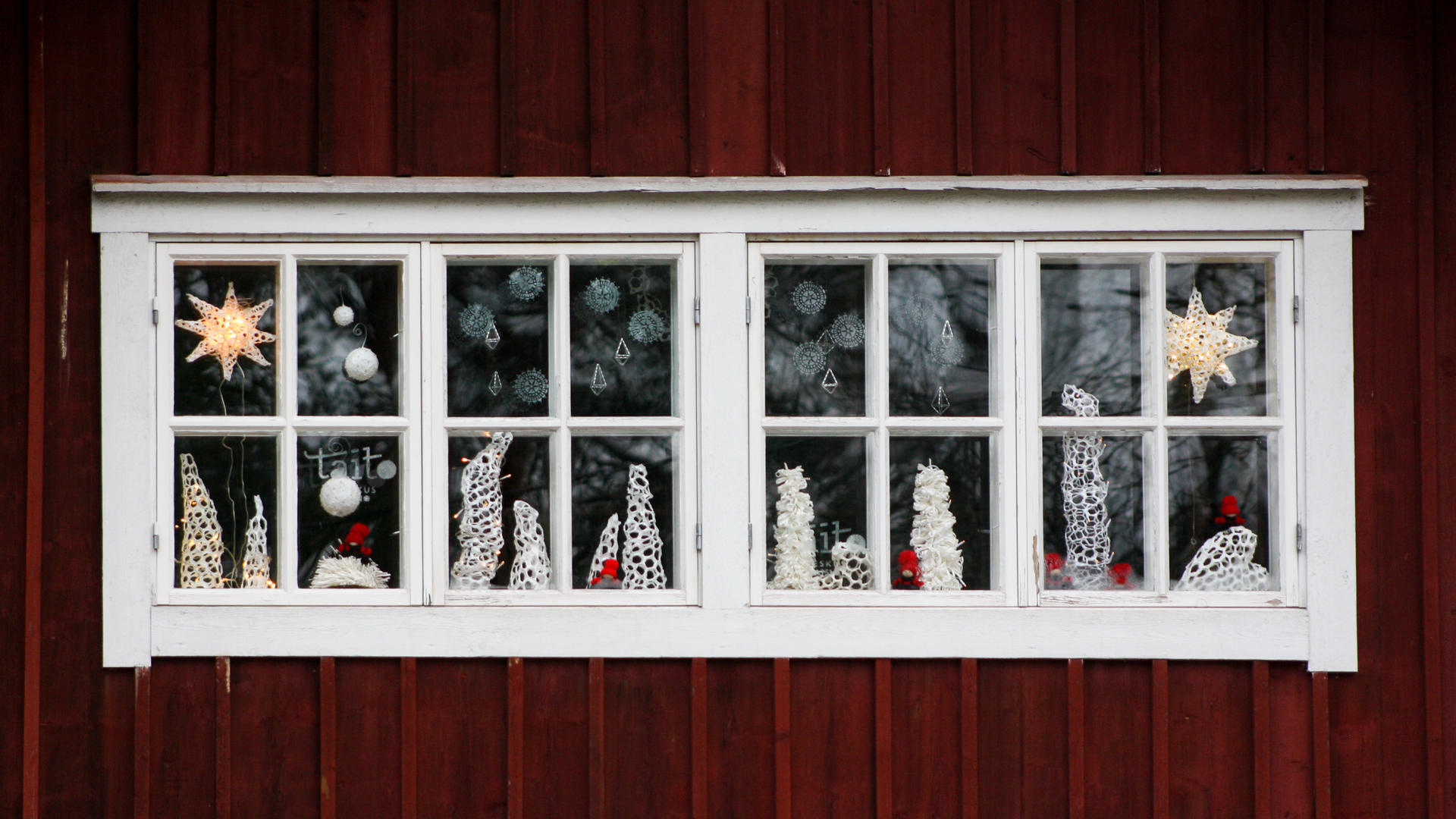 Taitokeskuksen ikkuna, jossa näkyy joulukoristeita, kuten tonttuja, lumihiutaleita ja tähtiä.