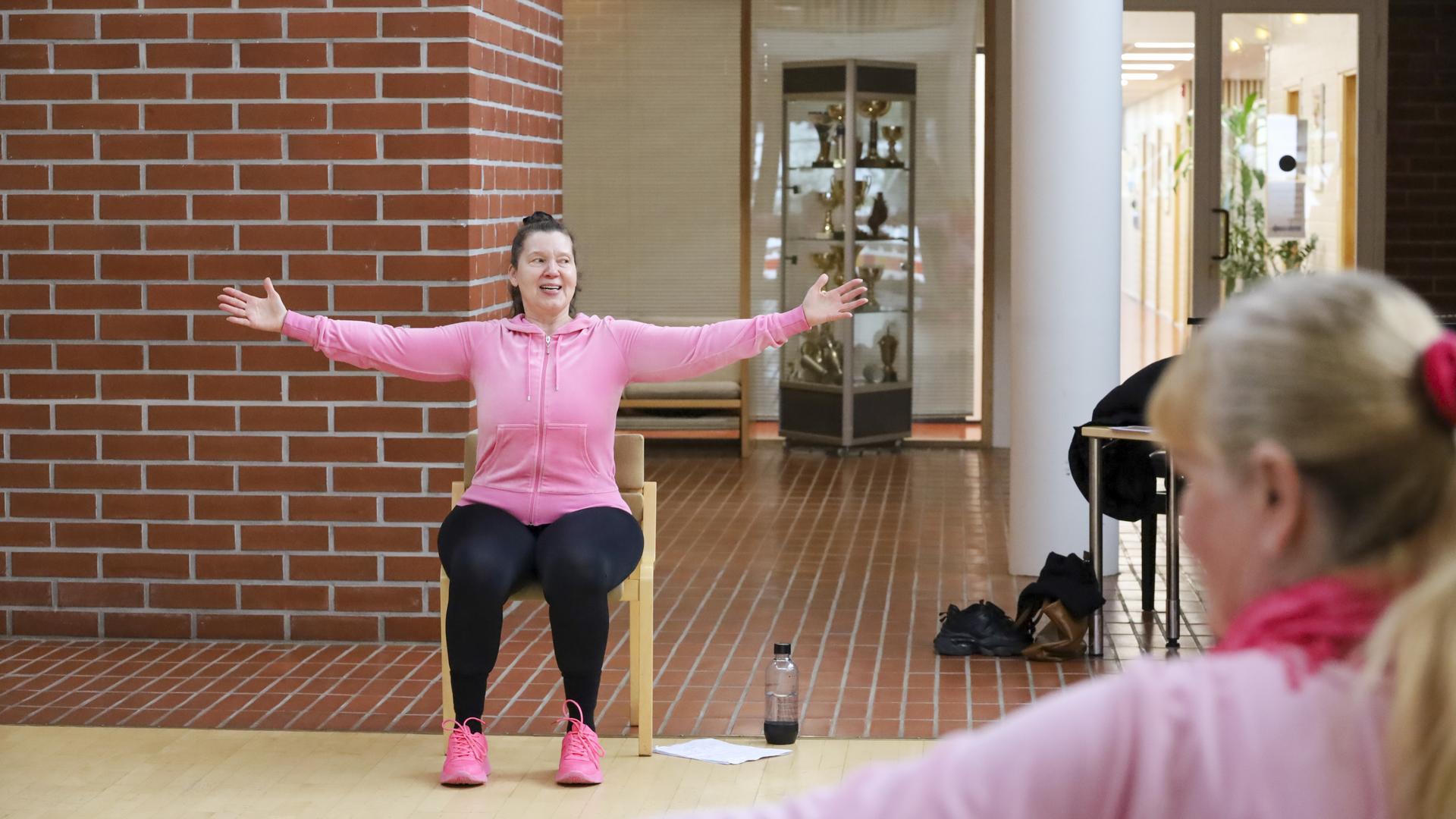 Henkilö ohjaa tuolijumppaa ryhmälle.