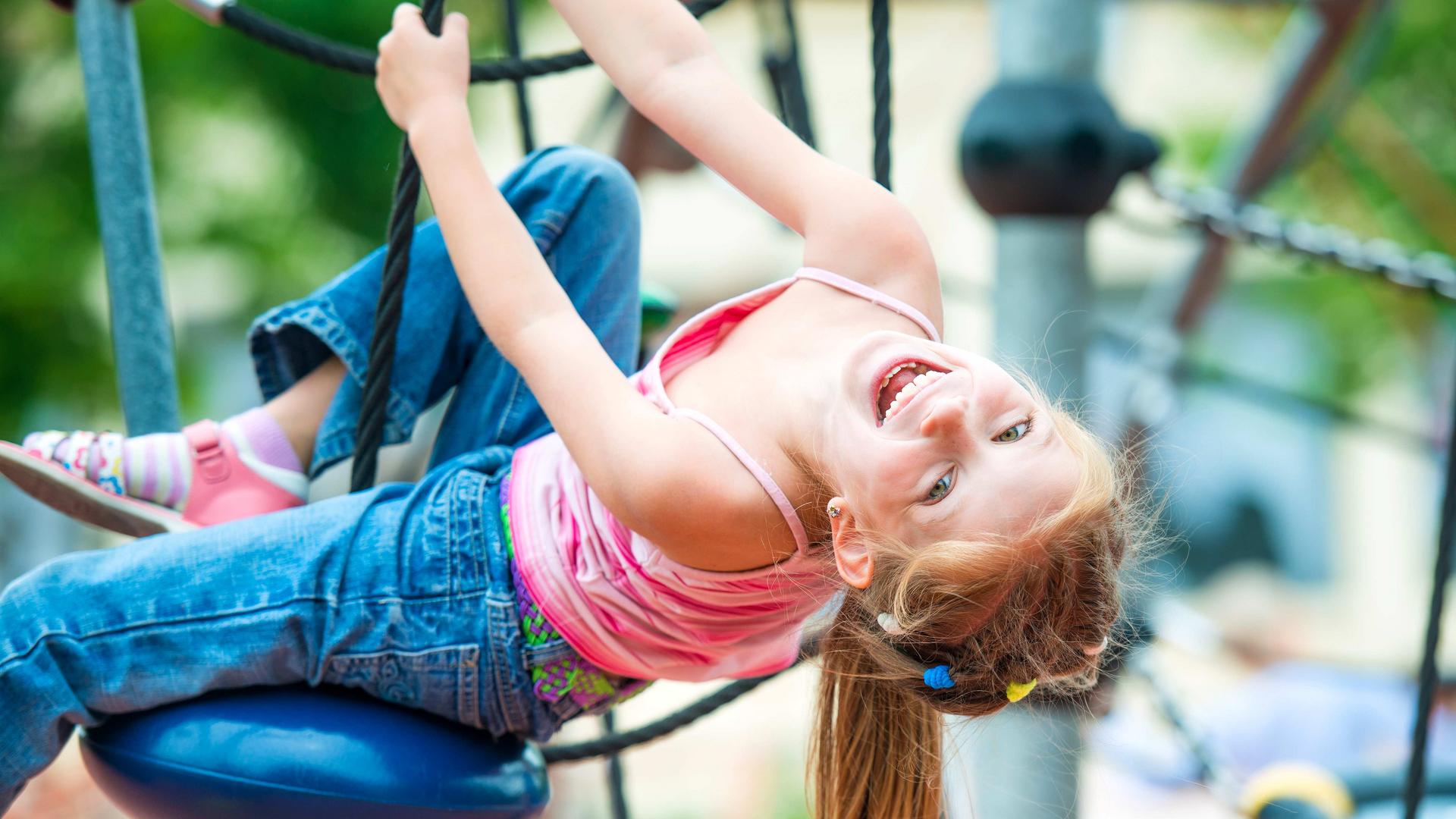 Tyttö kiipeää kiipeilytelineessä ulkona.