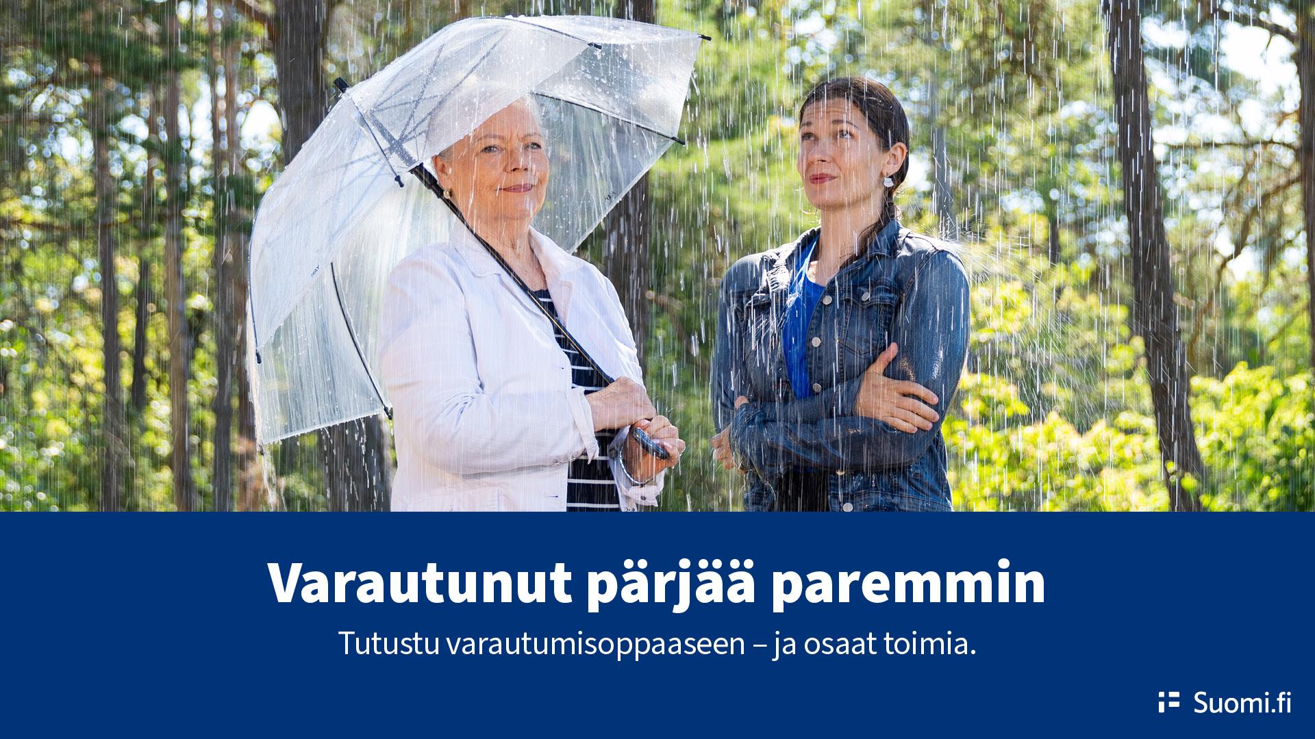 Kuvassa kaksi naista sateessa, toisella on sateenvarjo toisella ei. Kuva sisäministeriö.