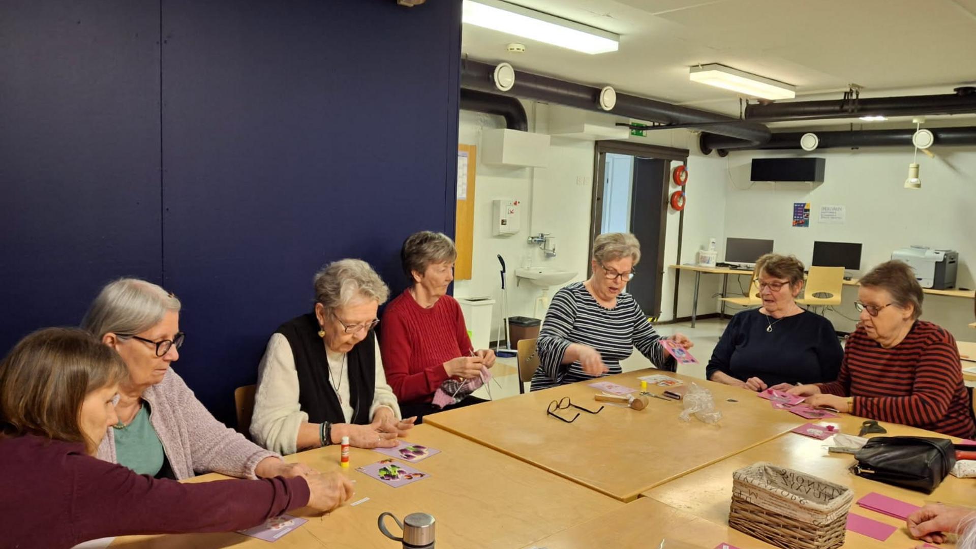 Jouko eläkeläisnaisia askartelemassa pöydän ääressä.