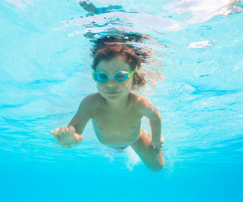 Pieni poika sukeltaa uimalasit päässä.