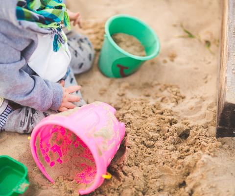 Lapsi leikkii kahdella ämpärillä hiekkalaatikolla.