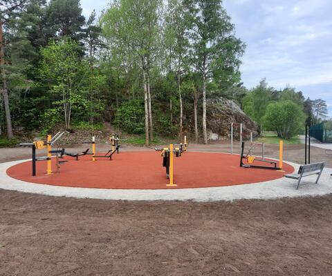 Ulkokuntosalilaitteita punaisen alustan päällä.