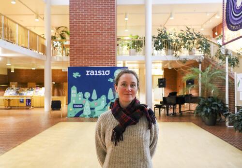 Kaupunginarkkitehti Emma Kaitaa seisoo kaupungintalon aulassa takanaan Raisio-kuvausseinä. 