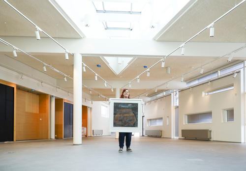 Kirsi Leimu pitää uusissa museotiloissa käsissään taideteosta näyttelystä Linnunradan alla – Eläimiä taiteessa ja taruissa.