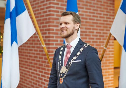 Eero Vainio Suomen lippujen edustalla käädyt kaulassa.