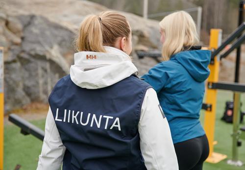 Liikuntaohjaaja neuvoo henkilöä ulkoliikunpaikassa.