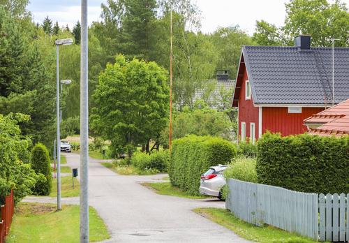 Kesäinen katumaisema, jossa punainen omakotitalo
