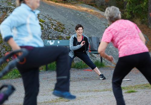 Ohjaaja pitää jumppatuokiota puistossa.