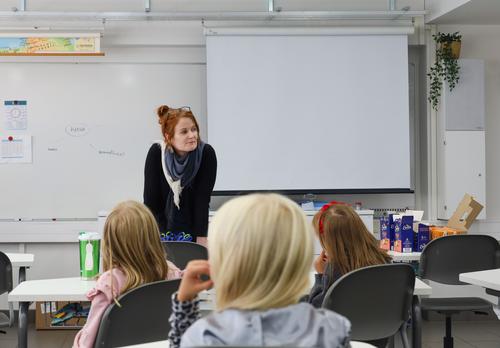 Ohjaaja pitämässä käsityökerhoa lapsille koululuokassa.