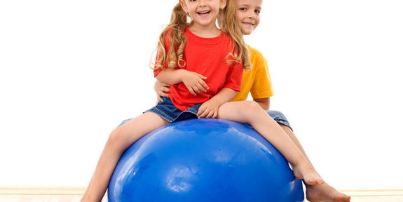Kaksi lasta jumppapallon päällä.