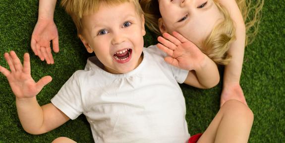 Kaksi lasta nauraa lattialla maaten