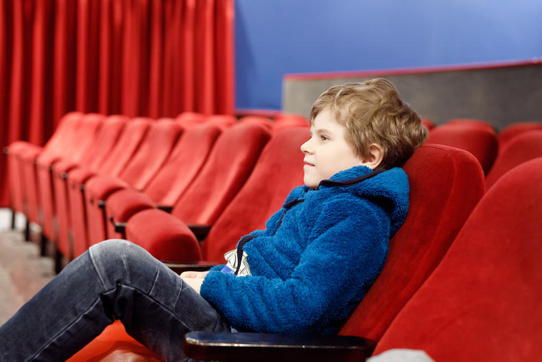 Pieni poika istuu yksin elokuvateatterissa.