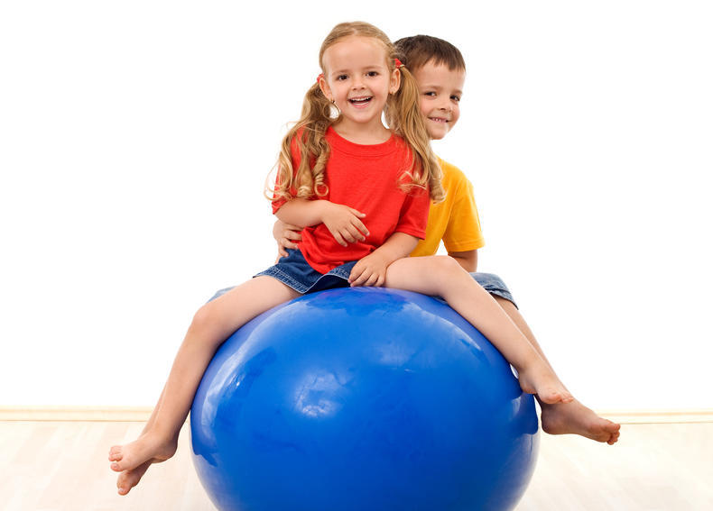 Kaksi lasta jumppapallon päällä.