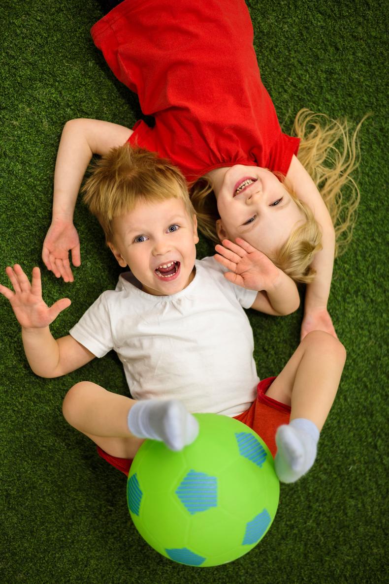 Kaksi lasta nauraa lattialla maaten