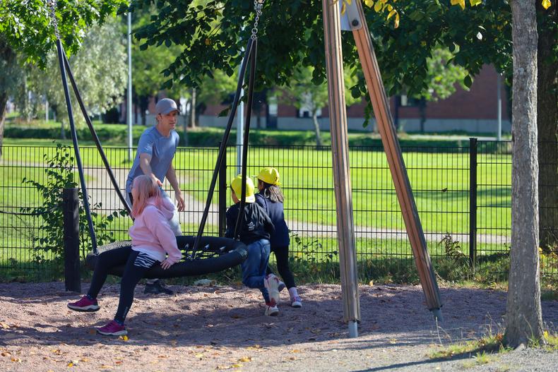 Lapset leikkimässä pihaleikkejä leikkipuistossa ohjaajan kanssa. 