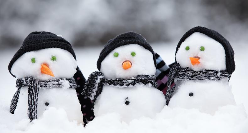 Kolme pientä lumiukkoa hangessa.