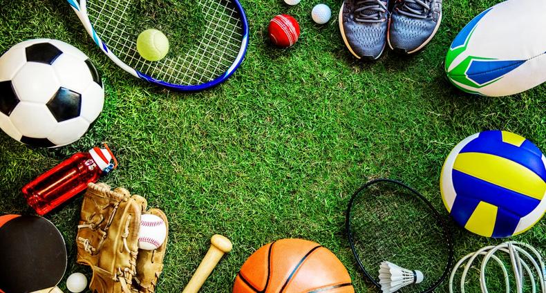 Vihreällä nurmikolla erilaisia palloja ja mailoja.